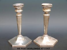 A pair of hallmarked silver candle sticks with tapering shafts raised on hexagonal bases,