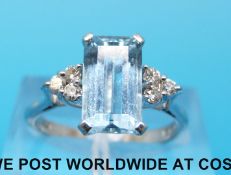An 18ct white gold ring set with an emerald cut aquamarine and three diamonds to either side (size