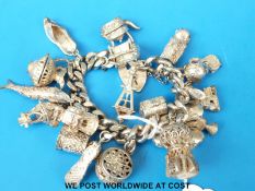 A large silver charm bracelet with various charms including a fish, golf clubs, a church, shoes,