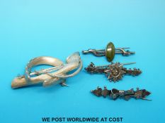 A white metal brooch in the form of a horseshoe, hoof and whip,