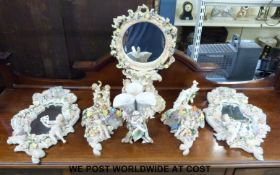 A quantity of German porcelain mirrors and ornaments all decorated with putti and flowers