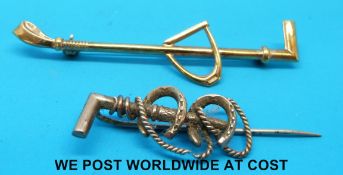 A gold brooch in the form of a stirrup and whip and one other