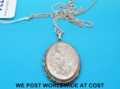 A silver locket with floral decoration on silver chain