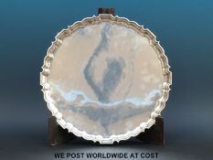 A hallmarked silver salver with gadrooned edge raised on four lions paw feet,