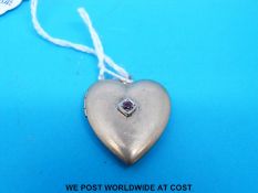 A yellow metal locket marked 10k in the shape of a heart set with a ruby to the centre
