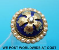A yellow metal ring set with blue guilloche enamel and a central diamond within a border of pearls
