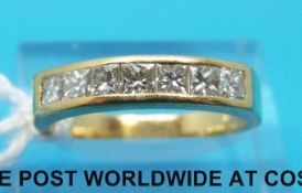 An 18ct gold half eternity ring set with princess cut diamonds in a bezel setting (size O)
