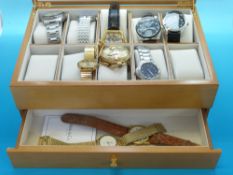 A glazed watch box containing a collection of modern gentleman's wrist watches