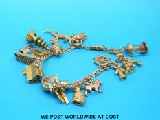 An 18ct gold charm bracelet with 16 charms, predominantly 9ct, including lizard,