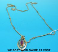 A yellow metal necklace with sphere and diamond decoration and pendant set with a ruby (7.