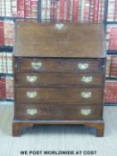A Georgian oak bureau with fitted interior and four graduated drawers raised on bracket feet (width