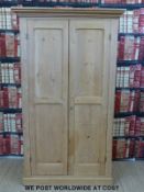A pine housekeeper's or similar cupboard, the panelled doors opening to reveal shelves (width 103cm,