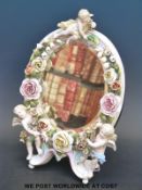 A 19thC German figural mirror with putti and flower surround, probably Sitzendorf or Volkstedt,