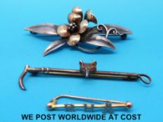 A silver brooch depicting a fox and whip,