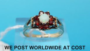A 9ct gold ring set with an opal surrounded by garnets (size P)