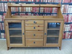 A pine sideboard with shelf above and four central drawers flanked by cupboards (width 141cm,