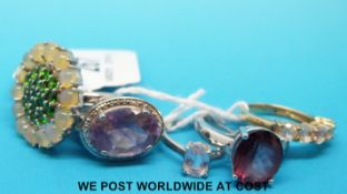 Four silver rings, one set with opals and peridot, one ruby,