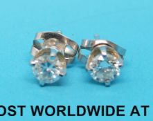 A pair of white metal earrings marked 14k set with a round brilliant cut diamond to each