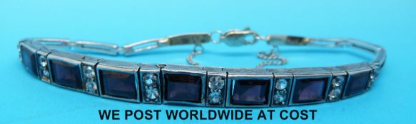 A white metal bracelet marked 14k set with garnets and white sapphires