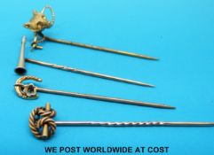 Four yellow metal stick pins, one in the form of a hunting horn,