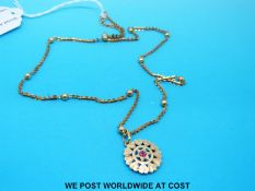 A yellow metal necklace with sphere decoration and pendant set with a ruby (7.