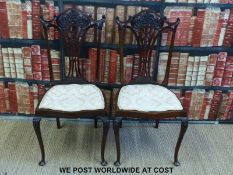 A pair of mahogany dining chairs with carved detail to backs