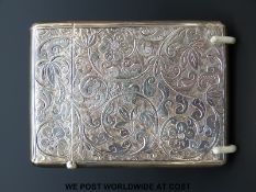 A hallmarked silver card case with engraved scrolling floral decoration and a vacant cartouche,
