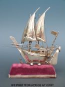 A white metal sailing ship or galleon on velvet and white metal base,