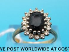 An 18ct gold ring set with a sapphire surrounded by clear stones (size Q)