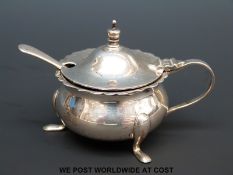 A hallmarked silver mustard raised on three feet with blue glass liner,