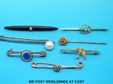 A yellow metal stick pin, marked 9k, set with a ruby in the form of a knot, yellow metal brooch,