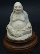 A carved ivory seated Buddha on turned base (height 6.