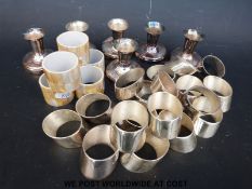 Six candle holders together with a collection of plated silver and shell napkin rings