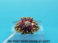 An 18ct gold ring set with a central diamond surrounded by rubies in a flower cluster with foliate