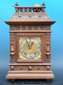 An oak cased mantel clock with bobbin turned gallery finial,