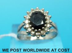 A white metal ring marked 18ct set with a large sapphire surrounded by diamonds (size N)