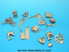 Eighteen 9ct/yellow metal charms to include dolphins, keys, heart padlock, ingot etc. (21.