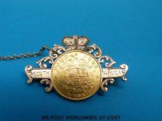 A yellow metal brooch reading South Africa set with an 1896 half pond (7.