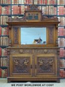 An Arts & Crafts or Art Nouveau carved oak sideboard with glazed small cupboard above the bevelled
