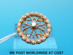 A yellow metal ring marked 14ct set with seed pearls in a circle and a diamond to the centre (size
