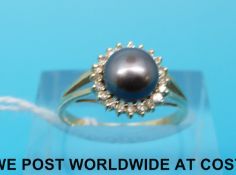 A yellow metal ring marked 585 set with a black Venetian pearl surrounded by diamonds (size L)