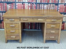 An oak pedestal desk fitted with nine drawers and two slides (width 153cm, depth 92cm,