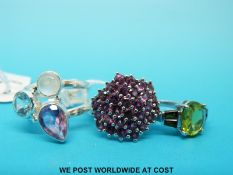 Three silver rings, one set with purple zircon in a cluster,