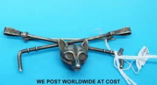 A white metal brooch in the form of a fox and riding crop