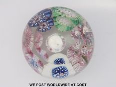 A millefiori glass paperweight with an Edward VII sixpence set to the centre surrounded by seven