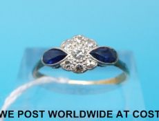 An 18ct gold ring set with diamonds in a cluster with two pear cut sapphires to the shoulders (size