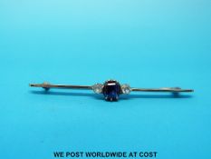 A yellow metal brooch set with a square cut sapphire flanked by white sapphires to each side