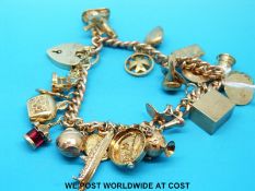 A 9ct gold charm bracelet with various 9ct / yellow metal charms including windmill, shoes, hat,