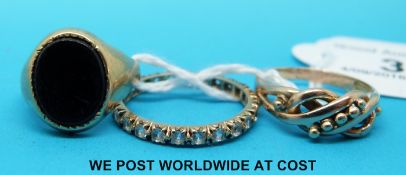 A 9ct gold signet ring set with onyx with two onyx and yellow metal rings,