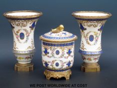 A hand decorated French porcelain ormolu mounted garniture bearing Sevres marks (tallest piece